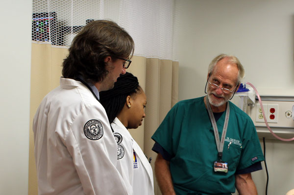 Two osteopathic medical students listen to a professor in the simulation center.