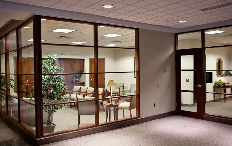 Office waiting area with big windows separating hallway