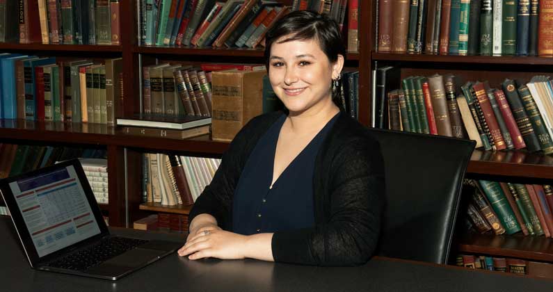 Julie Boyle (PsyD '20) poses with her research laptop in a PCOM library room