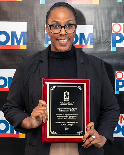 PCOM Georgia faculty member Dr. Shari Allen smiles as she holds her DEI award