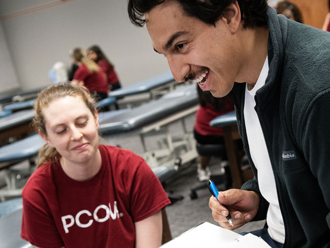 PCOM OMM students smile as they learn during a lab exercise