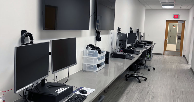 Sim Center control room with monitors, computers, keyboards, headphones and other equipment